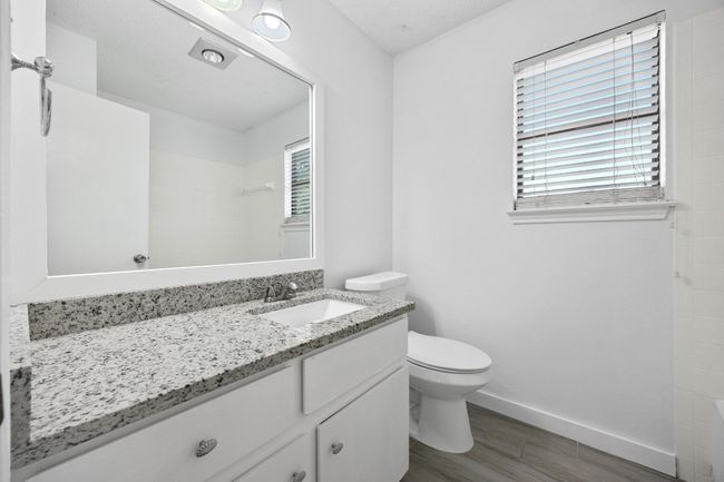 Bathroom featuring toilet, a tile shower, baseboards, wood finished floors, and vanity | Image 21