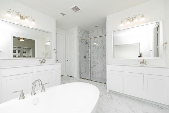 Full bathroom with marble finish floors, two vanities, a freestanding tub, a marble finish shower, and ceiling fan | Image 13