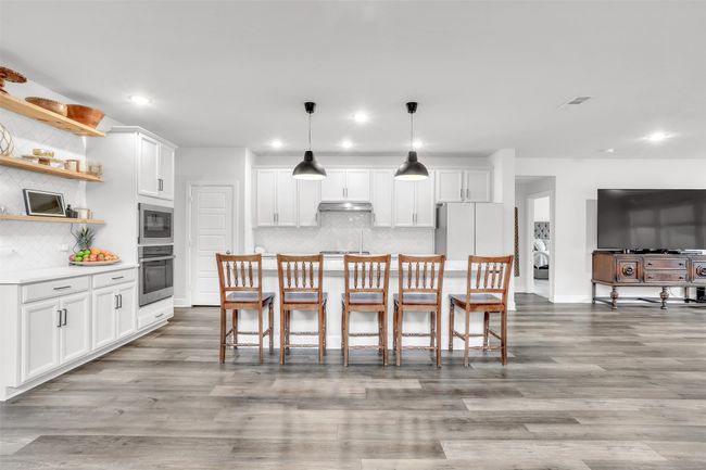 Kitchen featuring white cabinetry, pendant lighting, stainless steel oven, and white fridge | Image 9