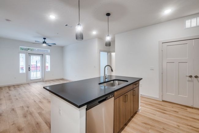 Kitchen featuring visible vents, a sink, stainless steel dishwasher, dark countertops, and light wood-type flooring | Image 22