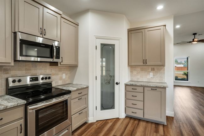 Kitchen featuring dark wood-type flooring, decorative backsplash, stainless steel appliances, and recessed lighting | Image 13