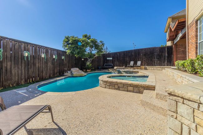 View of swimming pool with a patio area, a fenced backyard, and a pool with connected hot tub | Image 36