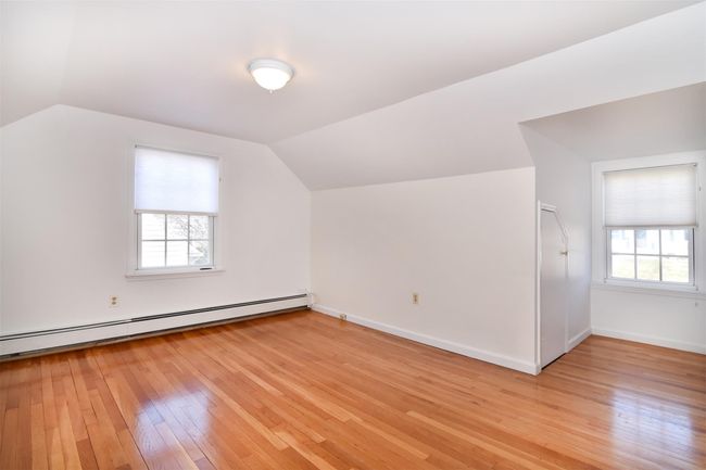 Additional living space featuring baseboard heating, a healthy amount of sunlight, lofted ceiling, and light wood-style floors | Image 17