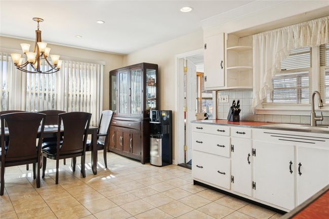 Kitchen featuring an inviting chandelier, white cabinets, a healthy amount of sunlight, and backsplash | Image 25