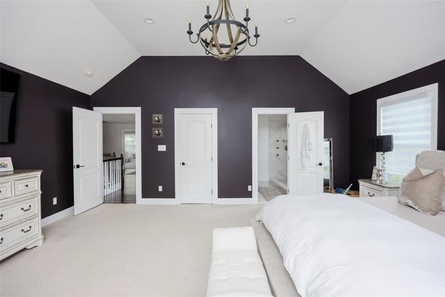 Bedroom with a chandelier, light carpet, high vaulted ceiling, and ensuite bath | Image 23
