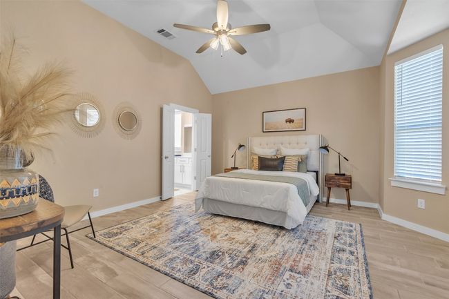 Bedroom with vaulted ceiling, light wood-style flooring, ensuite bathroom, and a ceiling fan | Image 17