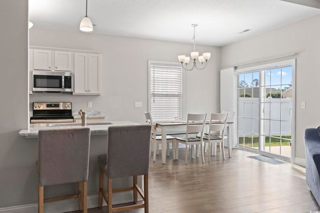 Kitchen with white cabinetry, a chandelier, decorative light fixtures, and stainless steel appliances | Image 15