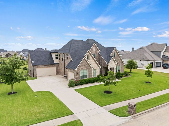 French provincial home with brick siding, concrete driveway, a front lawn, a residential view, and a garage | Image 21
