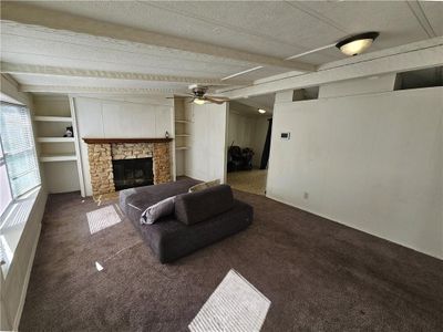 Carpeted living room with fireplace, ceiling fan, and lots of natural light | Image 3