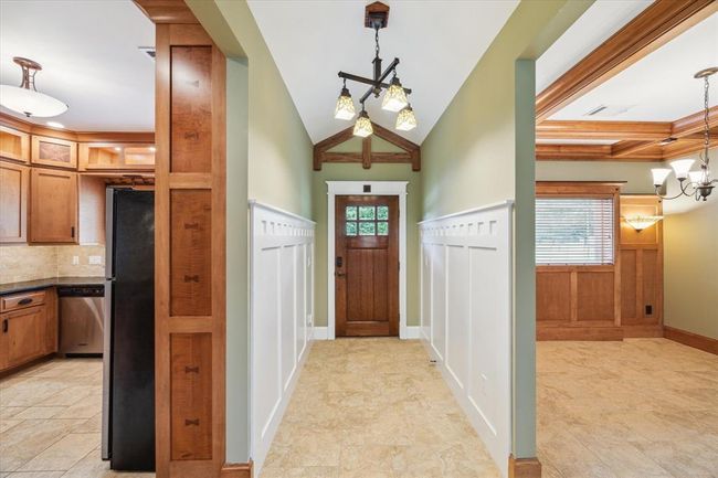 THIS STUNNING FRONT DOOR, CUSTOM STAINED IN RICH WALNUT, MAKES AN UNFORGETTABLE FIRST IMPRESSION. IT'S BEAUTIFULLY ACCENTED WITH ELEGANT LEADED GLASS PANELS AND FRAMED BESPOKE MOLDING THAT ENHANCES ITS ARCHITECTURAL CHARACTER. THE EXQUISITE CHANDELIER CASTS LIGHT OVER THE PERFECTLY ETCHED PANELED WALLS. A HANDCRAFTED WOOD DETAIL ABOVE THE DOOR ADDS SOPHISTICATION TO THIS ENTRYWAY | Image 6