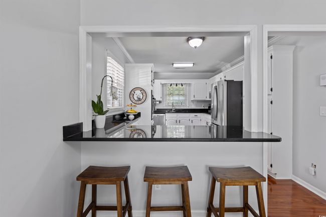Kitchen with appliances with stainless steel finishes, a peninsula, a sink, white cabinetry, and dark countertops | Image 11