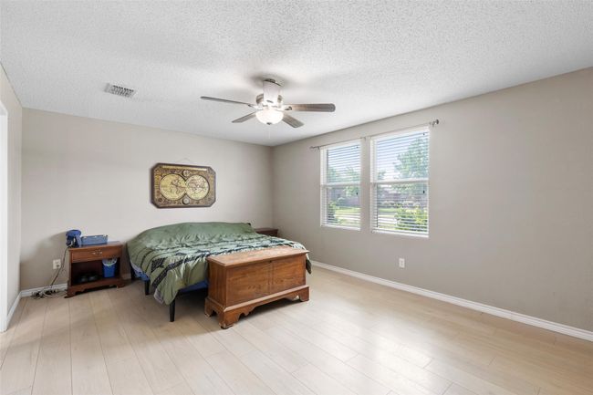Bedroom with ceiling fan, a textured ceiling, and light wood-type flooring | Image 12