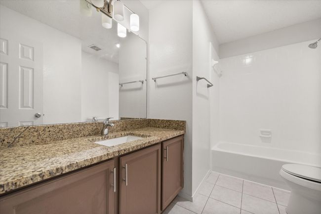 Bathroom featuring toilet, vanity, tile patterned flooring, shower / bathtub combination, and baseboards | Image 20