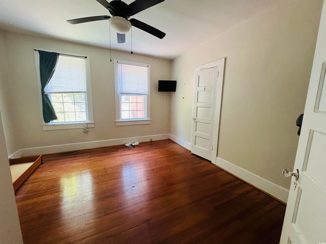Empty room with dark wood-style floors, baseboards, and a ceiling fan | Image 6