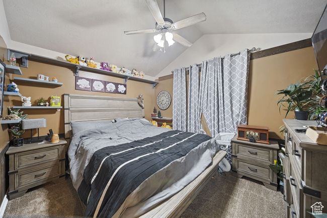 Bedroom with vaulted ceiling, dark colored carpet, and ceiling fan | Image 17