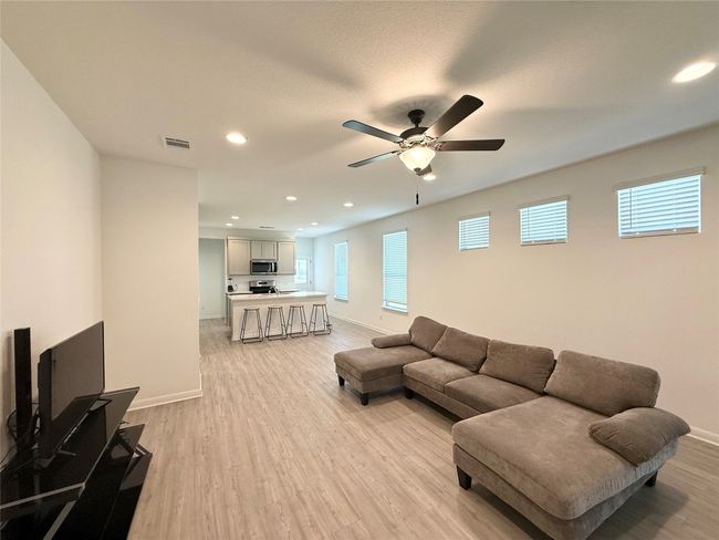 Living area featuring light wood-type flooring, baseboards, recessed lighting, and a ceiling fan | Image 5
