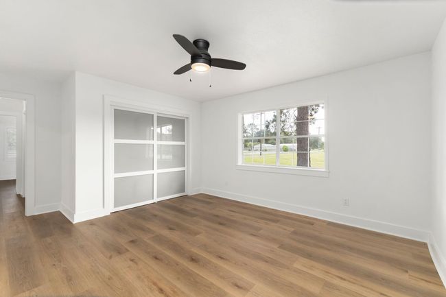 Bright and spacious bedroom featuring elegant flooring, a stylish ceiling fan, and ample natural light from the large window. Perfect for relaxation or productivity. | Image 32