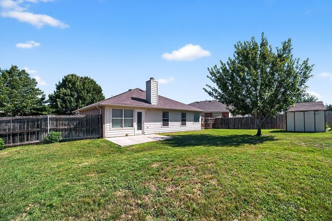Back of property with a storage unit, a fenced backyard, a chimney, and a patio | Image 35