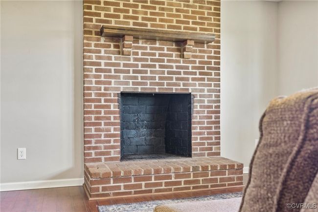 Room details with a brick fireplace, baseboards, and wood finished floors | Image 12