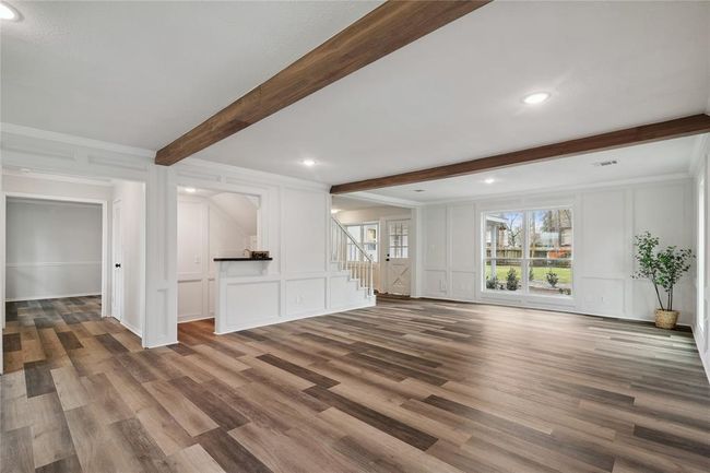 The family room has exposed beams, and large windows overlooking the backyard. The open layout includes a cozy wet-bar under the stairs. | Image 7