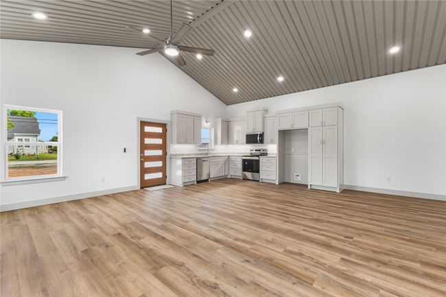 Unfurnished living room featuring high vaulted ceiling, baseboards, ceiling fan, light wood-type flooring, and recessed lighting | Image 11