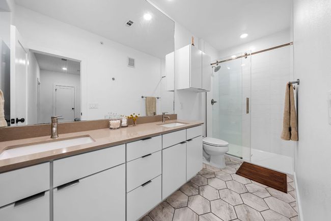 Full bathroom with a stall shower, double vanity, toilet, and a sink | Image 23