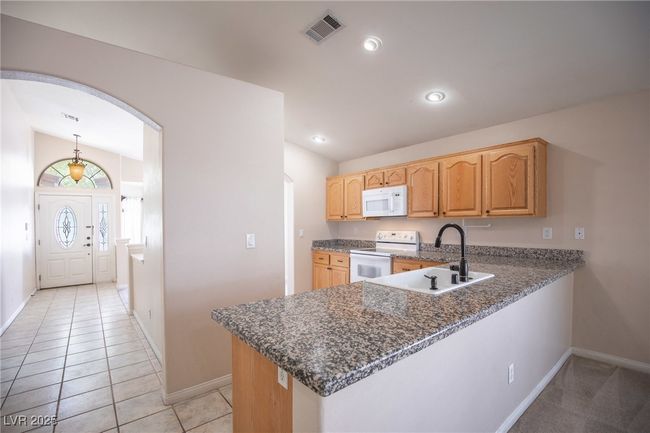 Kitchen featuring a sink, visible vents, baseboards, arched walkways, and white appliances | Image 12