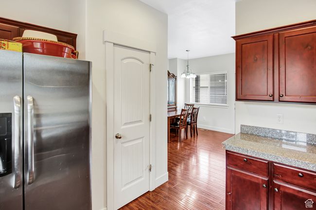 Kitchen with stainless steel refrigerator with ice dispenser, reddish brown cabinets, dark wood finished floors, and a chandelier | Image 14