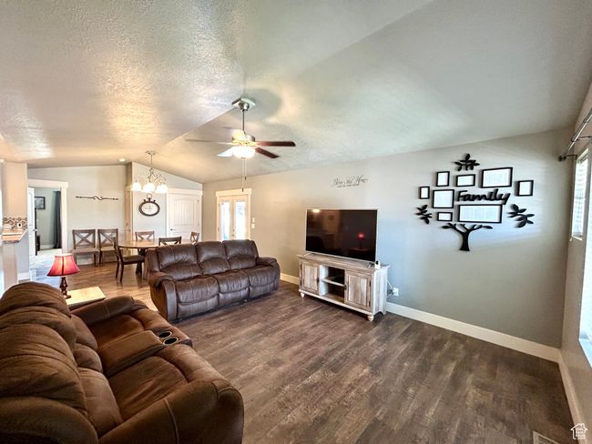 Living room featuring vaulted ceiling, dark wood-style floors, baseboards, a ceiling fan, and a textured ceiling | Image 7