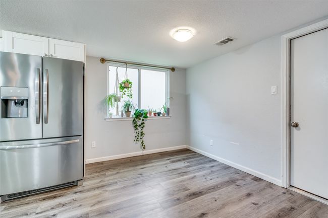 Kitchen with a textured ceiling, light hardwood / wood-style floors, white cabinets, and stainless steel fridge | Image 13