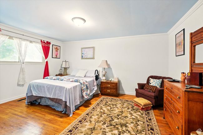 Bedroom featuring ornamental molding, wood finished floors, and baseboards | Image 18