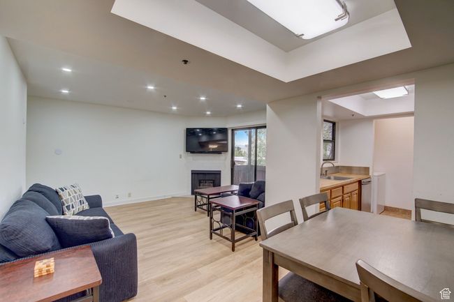 Living room with a raised ceiling, light hardwood / wood-style flooring, a fireplace, and sink | Image 5