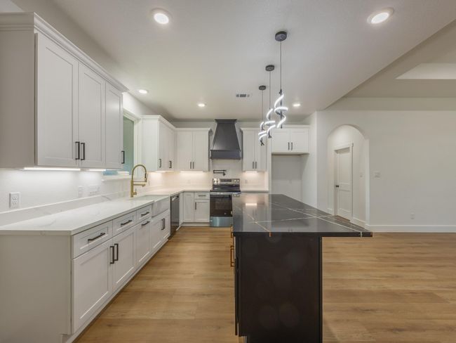 An abundance of cabinetry, deep drawers, and a walk-in pantry (not pictured) ensure this kitchen is as practical as it is beautiful. The black island with gold accents provides extra flair. | Image 14