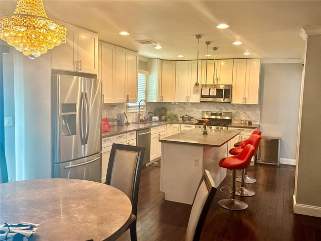 Kitchen with visible vents, stainless steel appliances, dark wood-style flooring, and a sink | Image 4