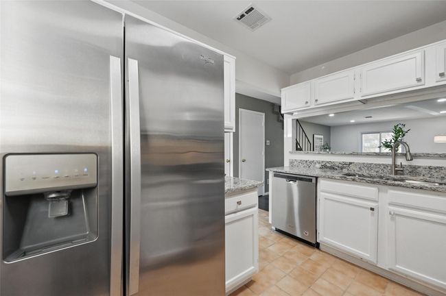 Kitchen with a sink, visible vents, white cabinets, and stainless steel appliances | Image 6
