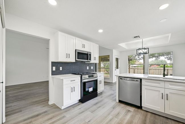 Kitchen with stainless steel appliances, light countertops, recessed lighting, healthy amount of natural light, and a tray ceiling | Image 13