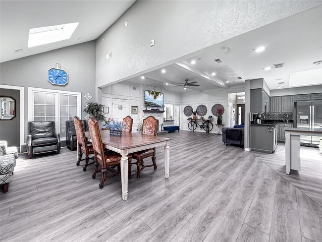 Dining area with light wood-type flooring, a ceiling fan, a skylight, recessed lighting, and high vaulted ceiling | Image 11