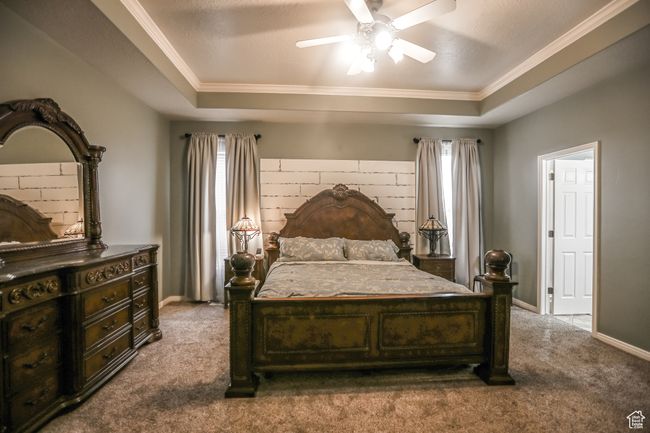 Bedroom featuring a tray ceiling, multiple windows, dark colored carpet, and ornamental molding | Image 22