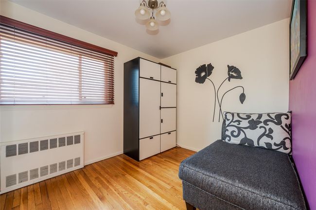 Bedroom with radiator heating unit, light wood-style flooring, a notable chandelier, and baseboards | Image 10