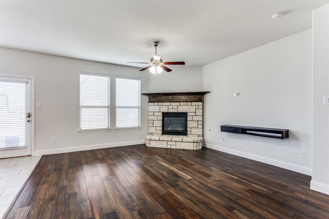 Unfurnished living room with a fireplace, ceiling fan, and dark hardwood / wood-style flooring | Image 8