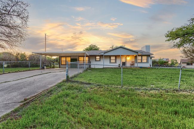 View of front facade featuring driveway, fence private yard, an attached carport, and a front yard | Image 34