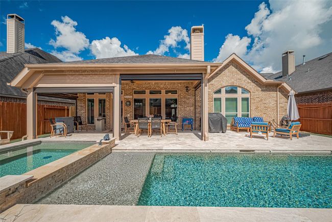 The expansive travertine decking around the pool creates multiple sitting areas, perfect for lounging, entertaining, or soaking up the sun. | Image 31