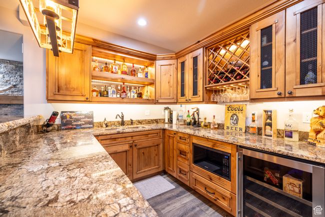 Indoor wet bar featuring wine cooler, black microwave, dark wood-type flooring, and recessed lighting | Image 41