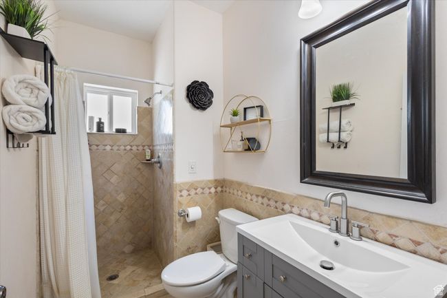 Bathroom with vanity, a shower stall, wainscoting, and tile walls | Image 12