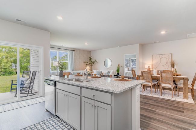 Kitchen with dishwasher, wood finished floors, a center island with sink, light stone countertops, and recessed lighting | Image 5