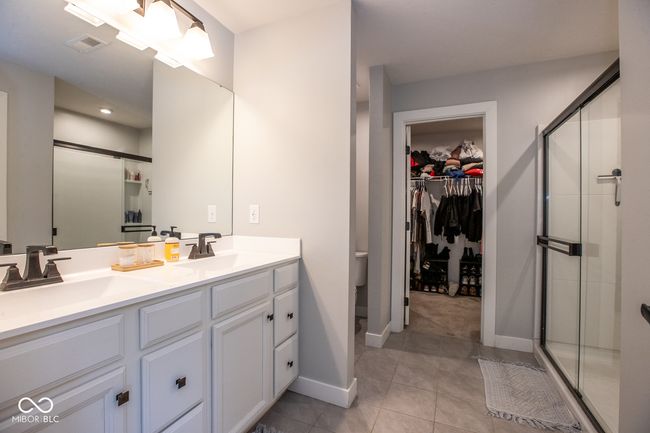 bathroom with tile patterned flooring, double vanity, a stall shower, and a spacious closet | Image 16