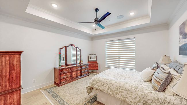 Bedroom with a raised ceiling, crown molding, light wood-type flooring, recessed lighting, and ceiling fan | Image 19