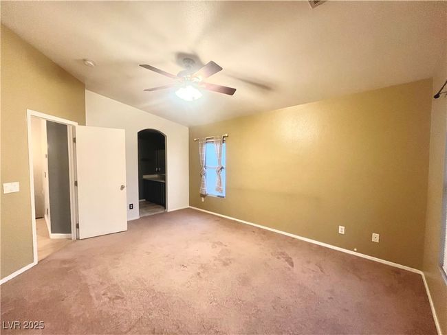 Unfurnished bedroom with vaulted ceiling, light carpet, baseboards, arched walkways, and ceiling fan | Image 12