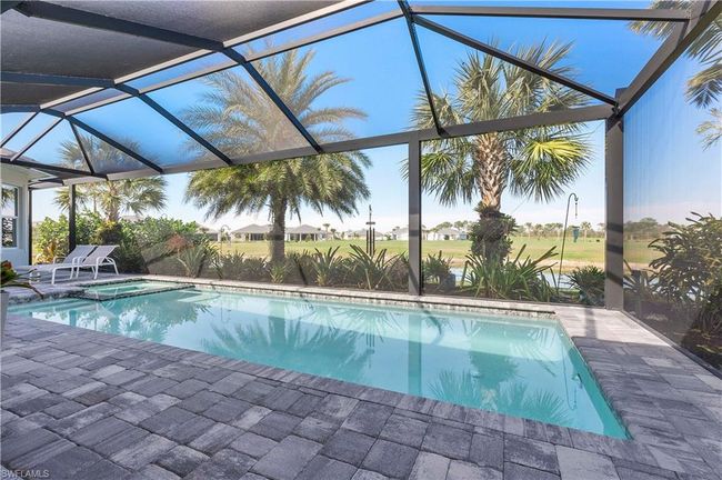 View of pool with glass enclosure, a pool with connected hot tub, and a patio area | Image 26