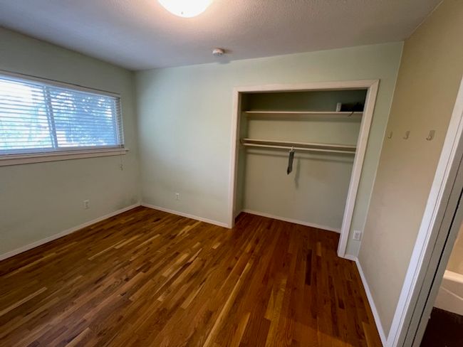 Unfurnished bedroom with a closet and wood finished floors | Image 10